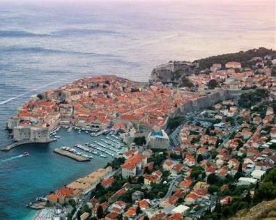 The walled Old Town of Dubrovnik features red-roofed buildings and a harbor surrounded by the Adriatic Sea in Croatia.