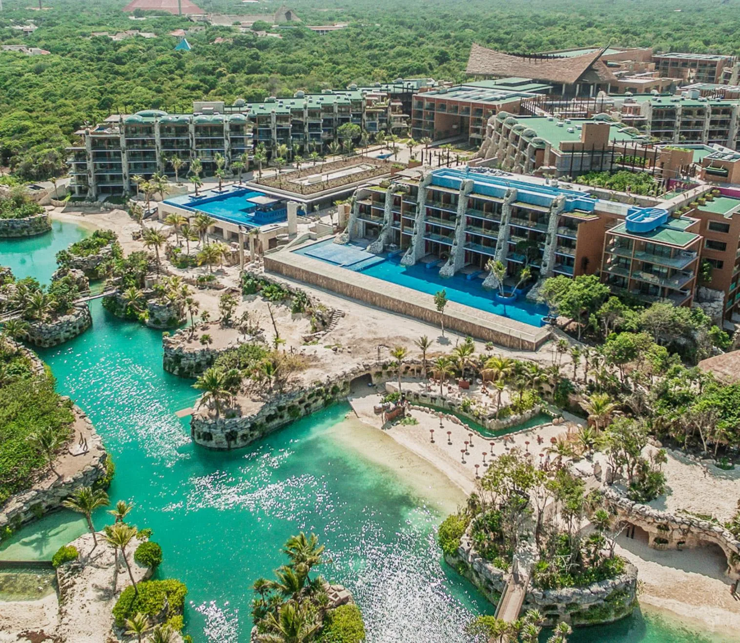 A sprawling resort with turquoise lagoons, tiered swimming pools, and rocky coves bordered by dense jungle in Riviera Maya.