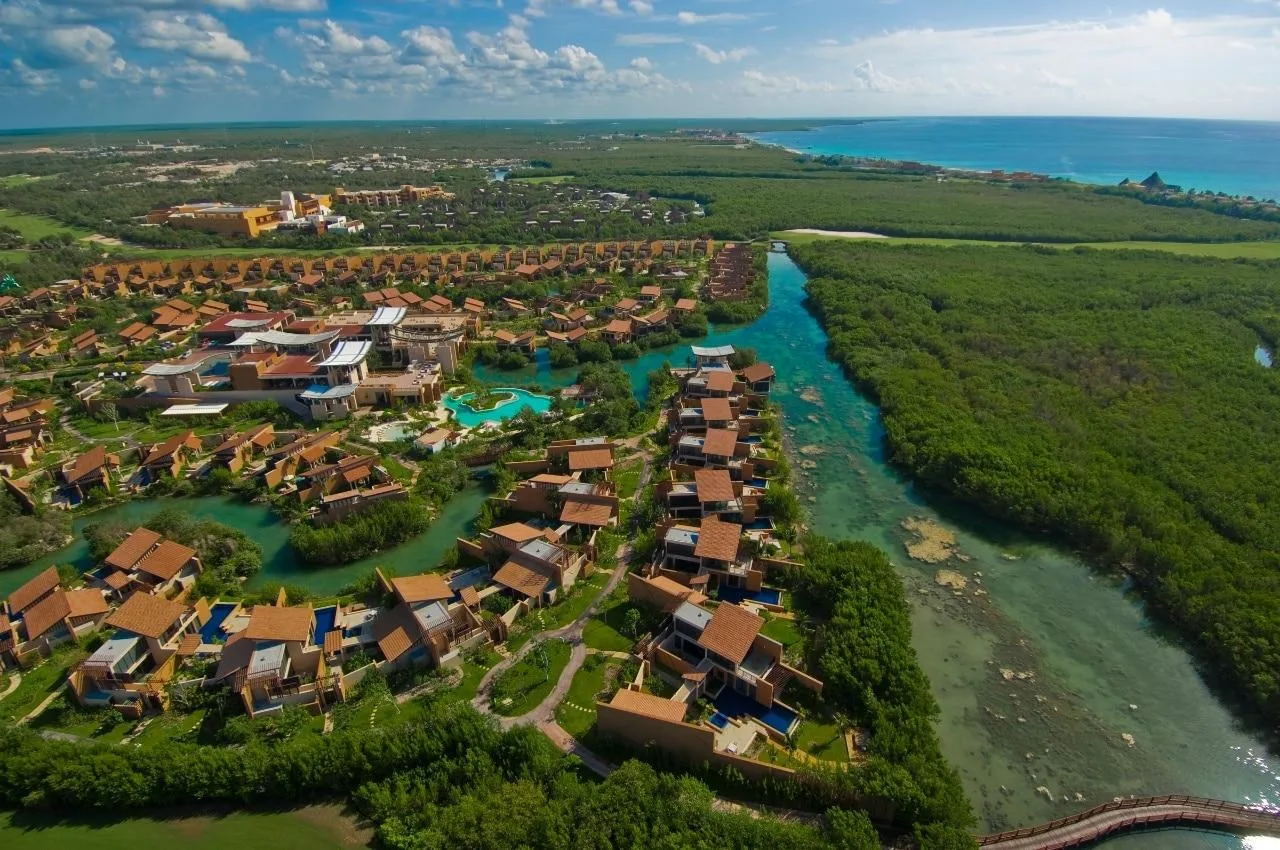 A luxury resort complex borders turquoise lagoons and lush mangrove forests along the coast in Riviera Maya, Mexico.