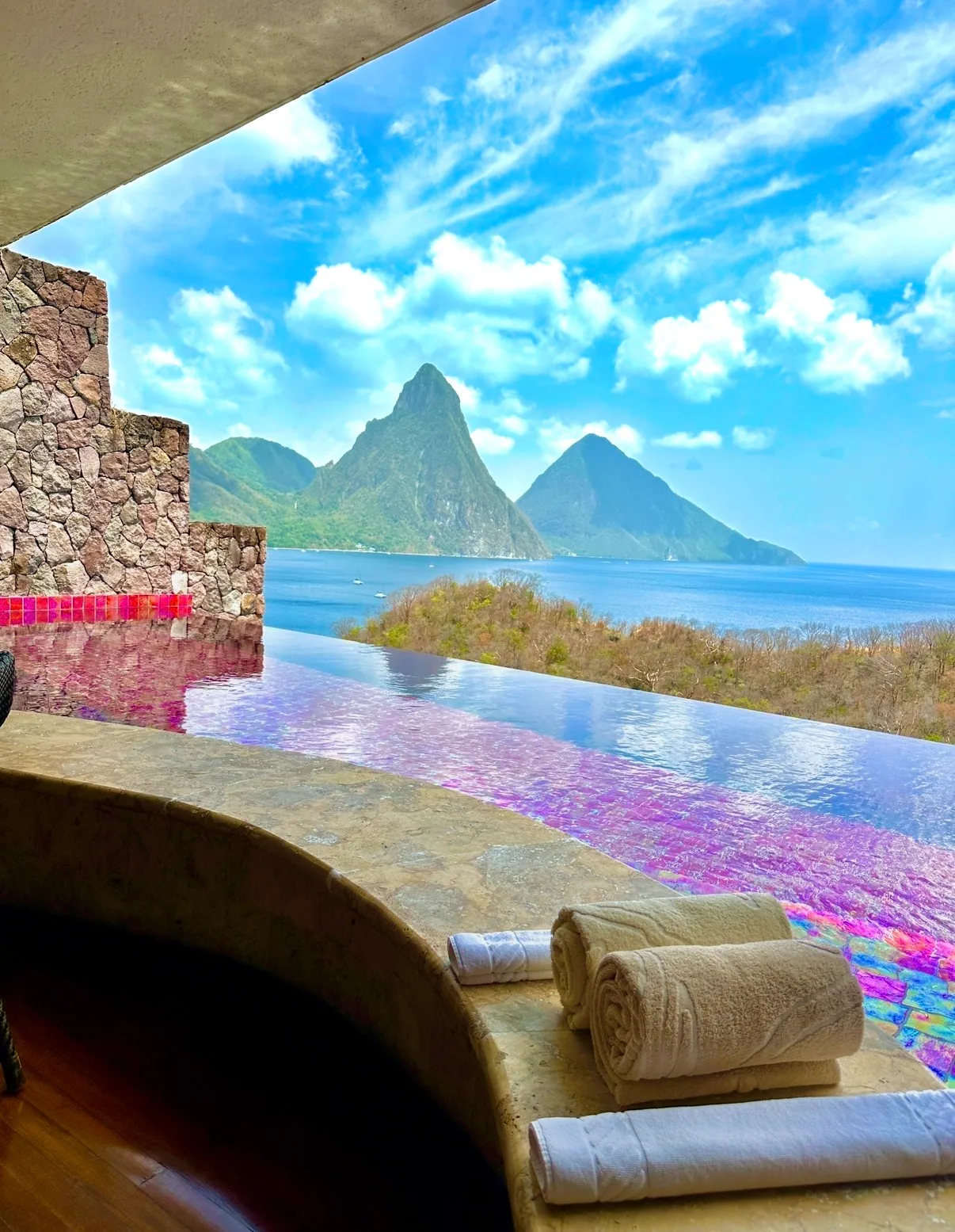 An infinity plunge pool on an open-air terrace overlooks the Piton mountains and Caribbean Sea in Saint Lucia.