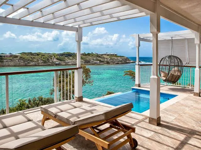 Sun loungers and a private plunge pool sit on a covered terrace overlooking turquoise coastal waters in Antigua.